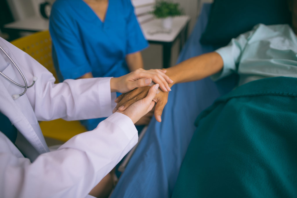 Doctor woman holding hand for reassuring her senior man patient.